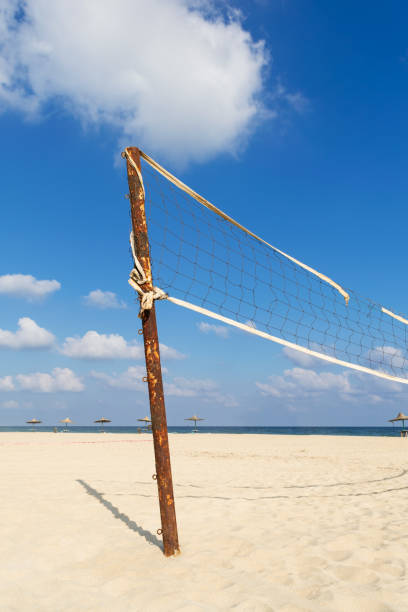istock Torn volleyball net on the beach with cloudy blue sky and yellow sand 1136634109