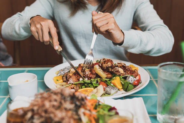 istock Young woman using knife and fork to cutting meat in restaurant 1136634585