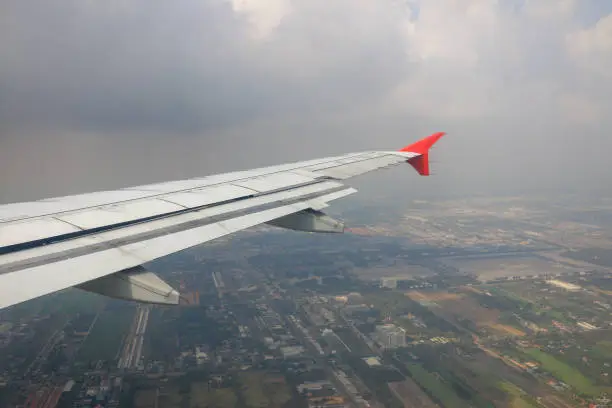 Photo of wing of airplane flying over agricultural area