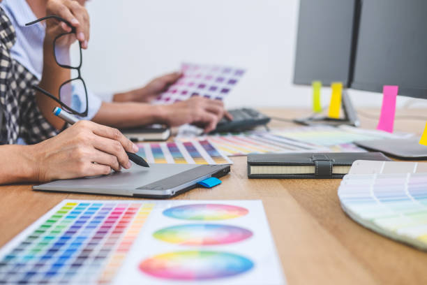 istock Two colleagues creative graphic designer working on color selection and drawing on graphics tablet at workplace, Color swatch samples chart for selection coloring 1136637500