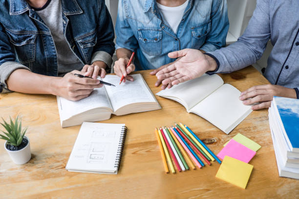 istock High school or college student group sitting at desk in library studying and reading, doing homework and lesson practice preparing exam to entrance, education concept 1136637509