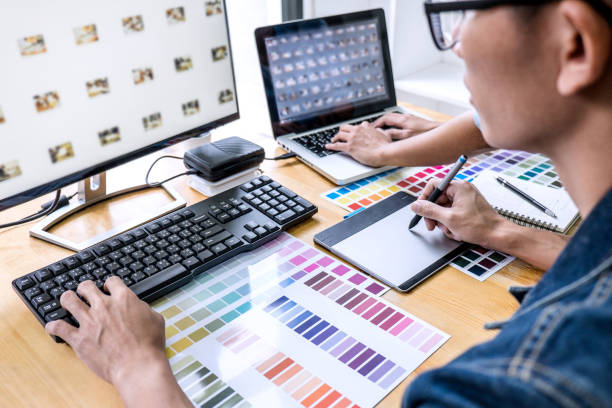 Team of young colleagues creative graphic designer working on color selection and drawing on graphics tablet at workplace, Color swatch samples chart for selection coloring