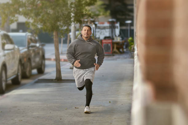 istock Determined male athlete jogging on sidewalk in city 1136637701