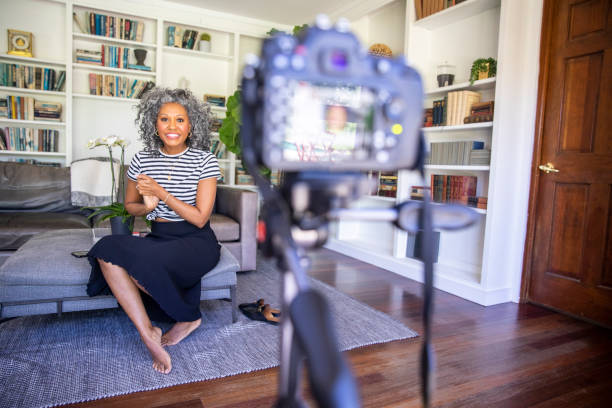 Beautiful Black Woman Recording a Video A beautiful black woman with white curly hair  sets up her camera and tripod to record a vlog for her blog persuasion photos stock pictures, royalty-free photos & images