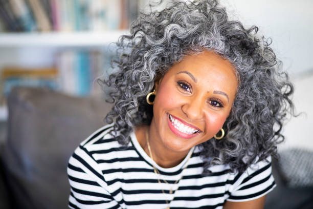 Closeup Headshot of a Beautiful Black Woman A beautiful black woman with white curly hair  smiles for a headshot Toothy Smile stock pictures, royalty-free photos & images