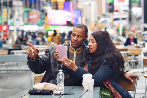 reife paar auf time square - digital tablet travel destinations new york state times square stock-fotos und bilder