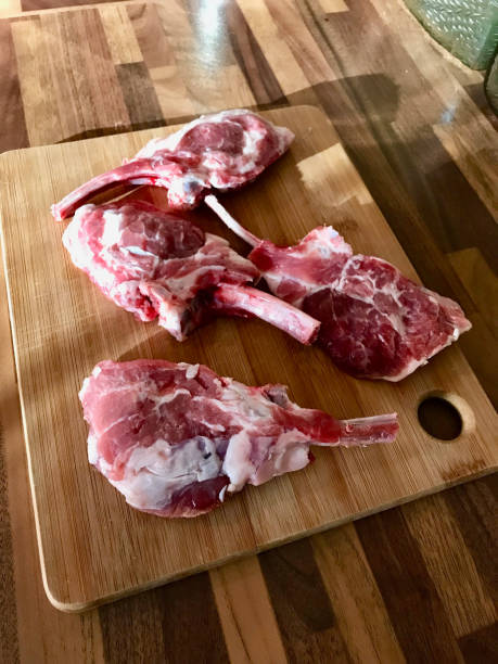 istock Raw Unfrozen Bloody Lamb Chops Meat on Wooden Board. 1136644427