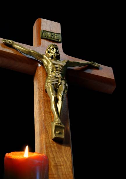 istock Crucifix with candle burning on black background 1136645798