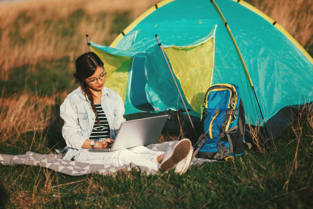 istock Young woman using laptop in the camp 1136645831