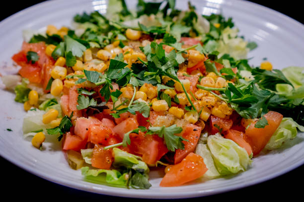 istock Fresh vegetable salad in a plate isolated on black background 1136648004