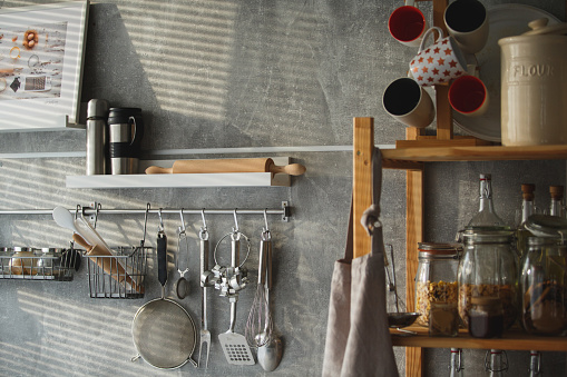 Kitchen utensils hanging on the wall. Shelves with kitchenware.