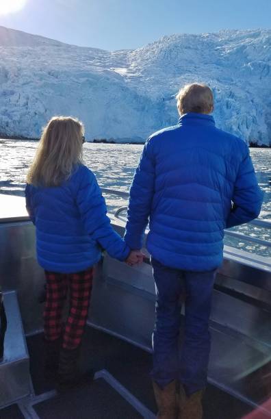 istock Adult Couple, Facing Ahead, and Holding Hands, While Observing a Large Glacier 1136652911
