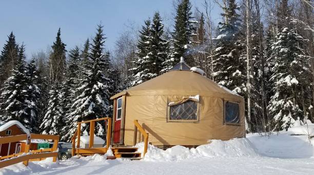 Small Circular Housing, a Yurt, in a Snowy Evergreen Setting stock photo
