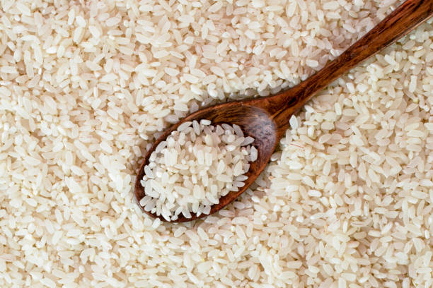 istock Rice background with wooden spoon close-up. The view from top. 1136653899