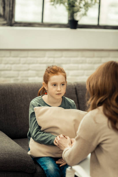 istock Cheerless young girl sitting opposite her therapist 1136654802