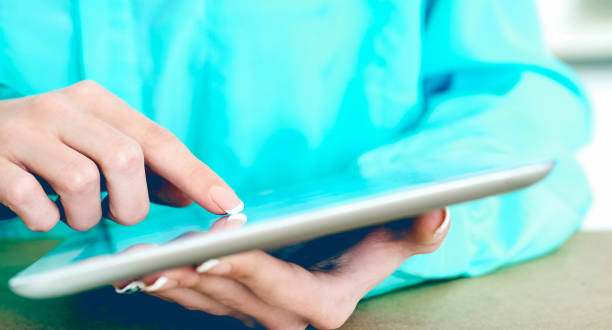 istock Close-up of female hands working with tablet computer. Woman using social network, texting and blogging. 1136656410