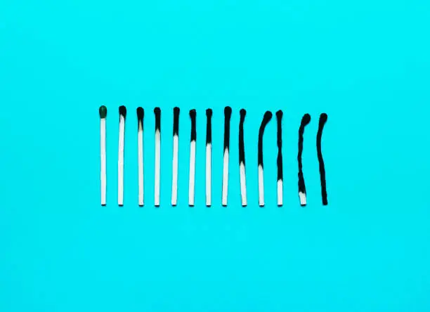 Photo of Burned matches in a row on a blue background.