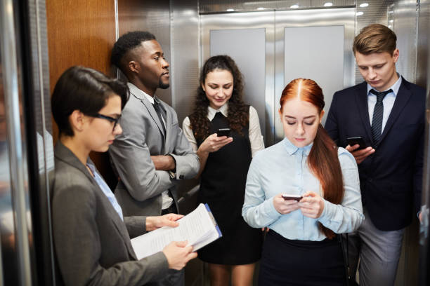 istock Group of office workers with phones in elevator 1136659789