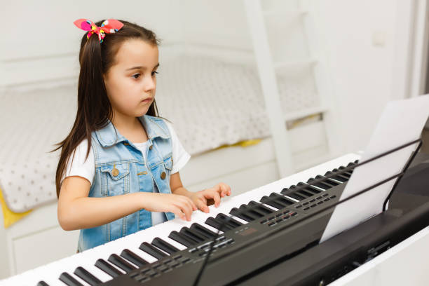 istock Happy Small Girl with the Piano Keyboard 1136660877
