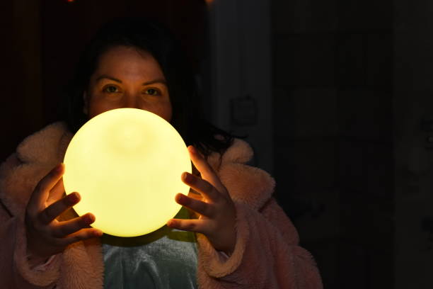 istock Young Woman with Soft Yellow Glowing Ball 1136664024