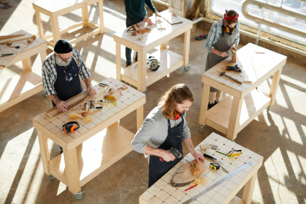 istock Serious concentrated manufacturing carpenters in aprons standing at desks and working with wood 1136664140