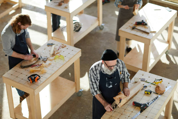istock Directly above view of serious senior bearded man in apron standing at table and using caliper while measuring thickness of log, he viewing unprocessed wooden planks 1136664143