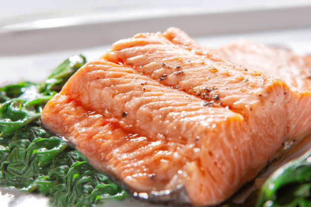 A piece of steamed salmon steak with spinach on a white background