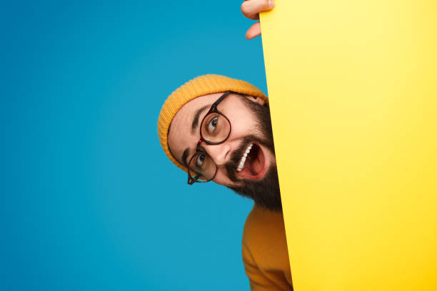 istock Cheerful man peeking out from behind poster 1136668118