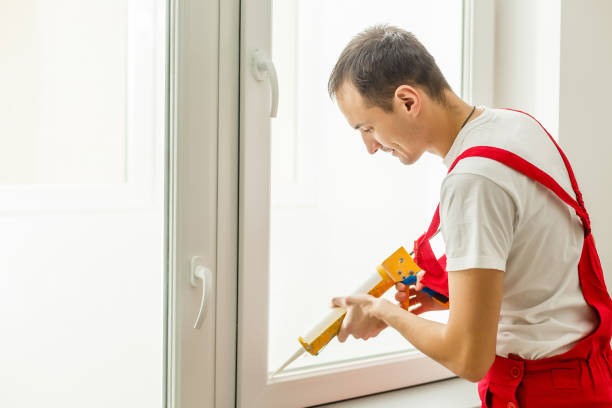 Construction worker putting sealing foam tape on window in house