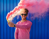 Contemporary ethnic man with bomb of colored smoke