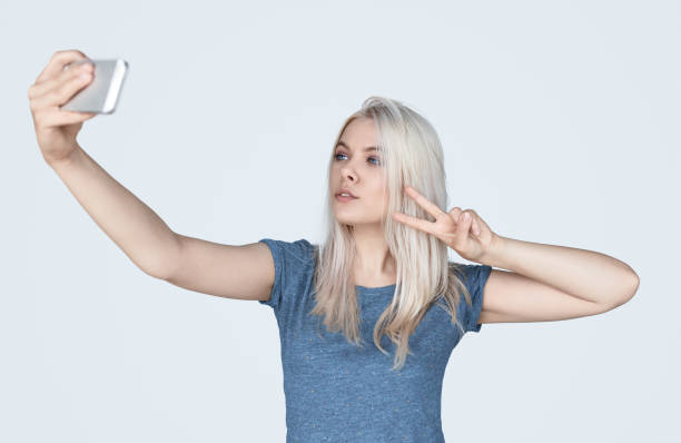 istock Casual blonde taking selfie and showing V-sign 1136669453