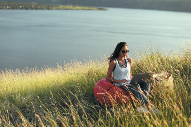 istock Girl with laptop on coast in sunlight 1136669467