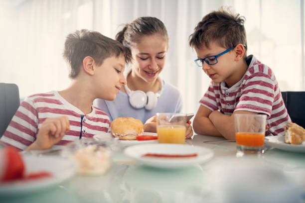 istock Thee kids eating breakfast and checking smartphone 1136670200
