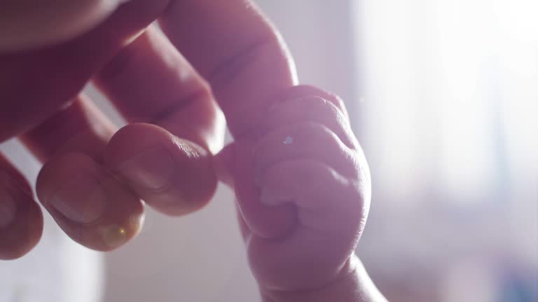 Newborn baby holding father's hand