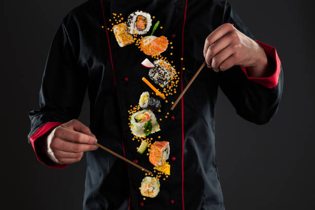 chopsticks mestres da terra arrendada do cozinheiro chefe com sushi do vôo - black dishware sushi isolated - fotografias e filmes do acervo