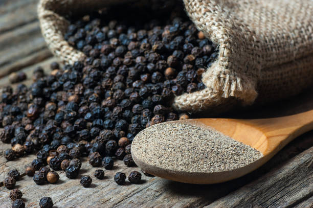 heap of black pepper and black pepper powder in wooden spoon - mortar and pestle condiment isolated food imagens e fotografias de stock
