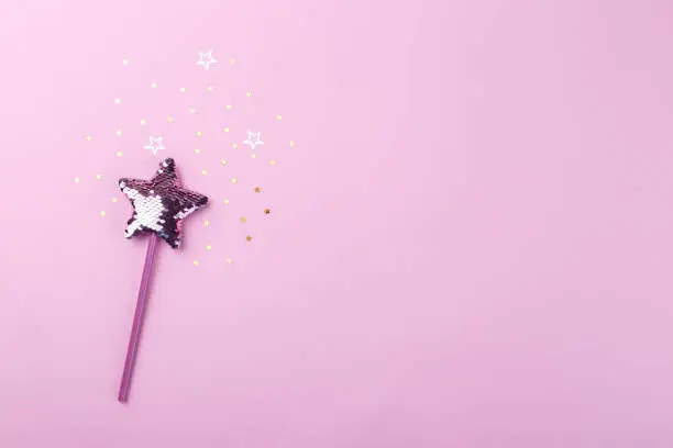 Sparkling magic wizard wand star shape on pink background, copy space
