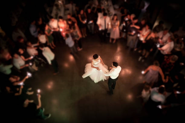 Top view on a wedding couple dancing the opening waltz at their wedding celebration. All their friends are standing in a ring around them with a light in their hands. Focus only on the bridal couple.