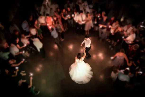Top view on a wedding couple dancing the opening waltz at their wedding celebration. All their friends are standing in a ring around them with a light in their hands. Focus only on the bridal couple.