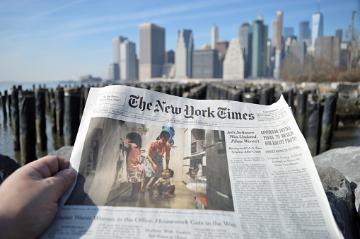 New York City, USA - February 3, 2019: The New York Times newspaper against a Lower Manhattan skyline.