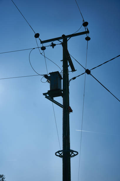 istock A wooden electrical power distribution post silhouetted against a blue sky 1136679374