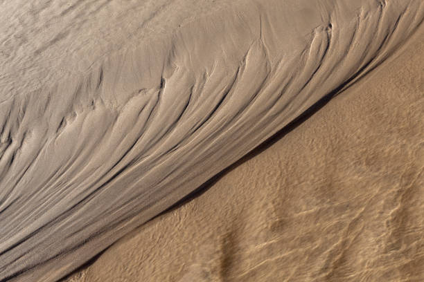 istock Natural Texture on beach sand left by water passage still flowing 1136681852