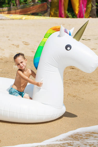 istock Boy with inflatable unicorn on the beach 1136687930