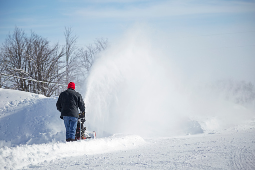 Erskine, USA - March 10, 2019: A man is operating a snow blower after a Minnesota blizzard.