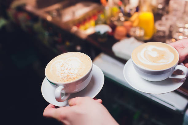 Unrecognizable waitress holding a cup of latte with rosetta in cafe.