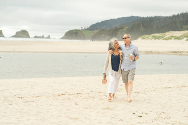 istock A senior couple walks barefoot along the beach and eats ice cream cones together 1136701174