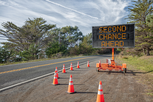SECOND CHANCE AHEAD: This is a photograph of a mobile roadside sign parked on highway one in northern California. It is a trailer and powered by batteries and provides information and warnings for drivers by displaying words on a large panel display.