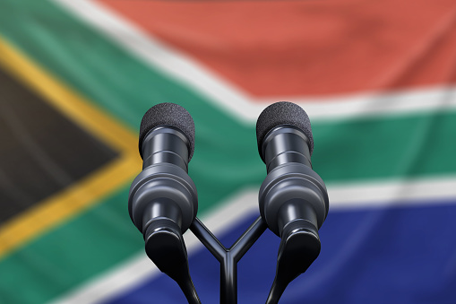 Podium lectern with two microphones and South Africa flag in background