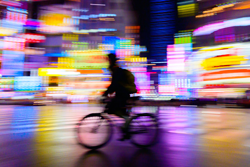 abstract speed motion blurred  of rider ride bicycle with neon light  from shinjuku,tokyo,japan  billboard background, urban night life