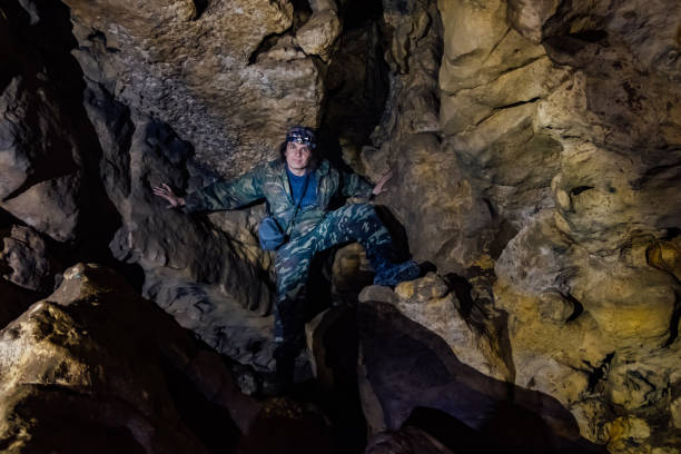 istock Man tourist in camouflage suit explores cave 1136715185
